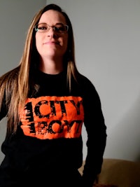 a woman in glasses wearing a city boy sweatshirt