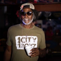 a man wearing sunglasses and a t - shirt holding a drink