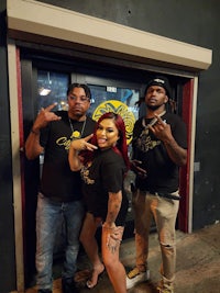 three people posing for a picture in front of a bar